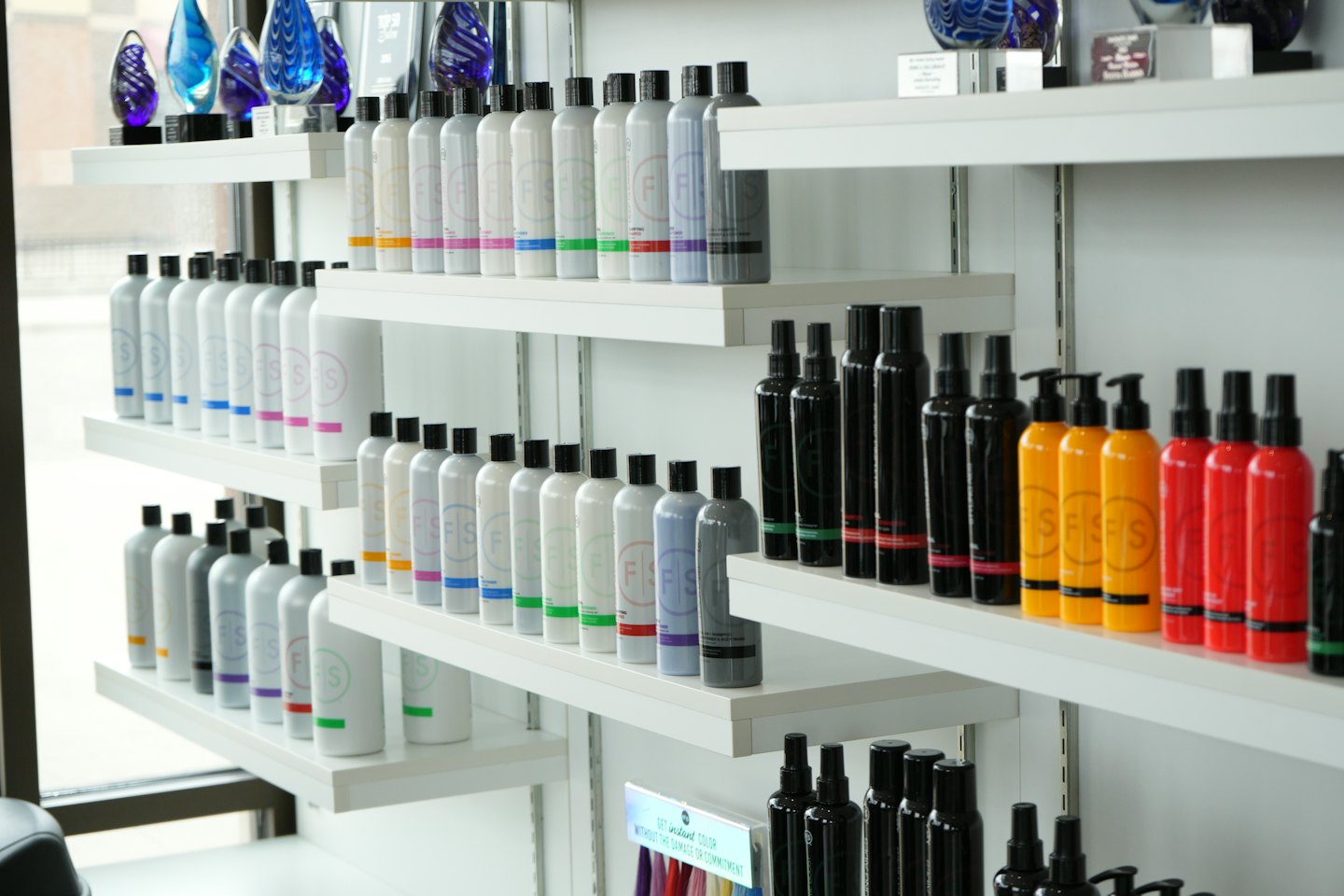 Retail shelves display neatly arranged hair care bottles and glass art.